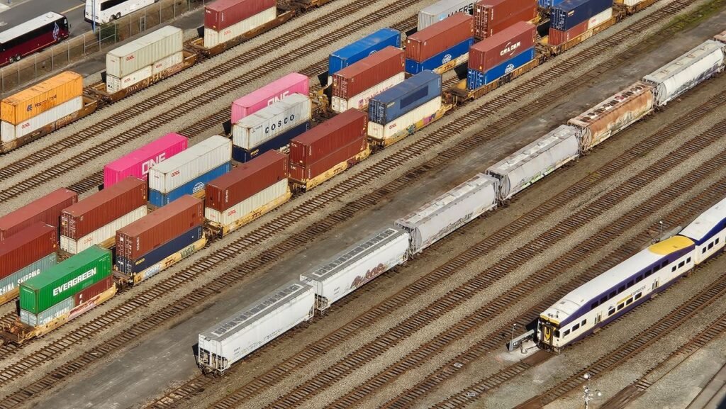 pexels-photo-27624035 Aerial shot showcasing colorful freight containers on train tracks in a busy transportation yard.